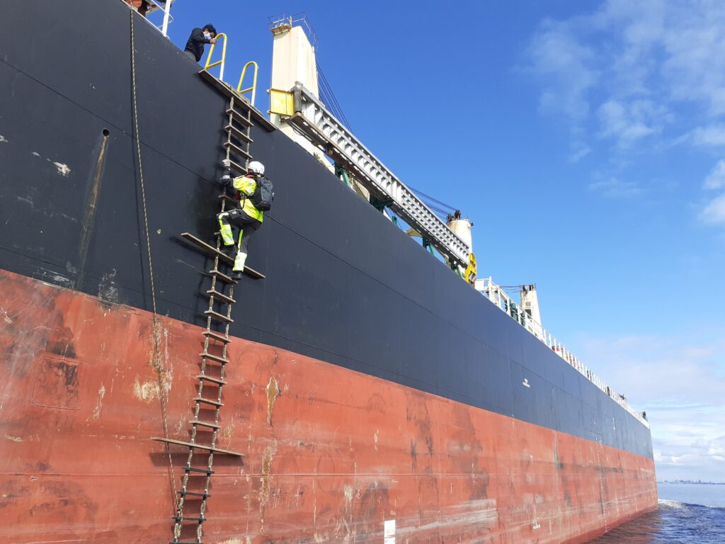 Luotsi leidareilla eli luotsitikkailla kiipeämässä laivaan